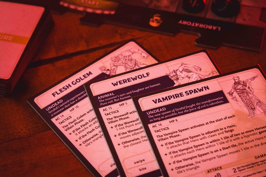 Three game cards displayed on a wooden surface with red lighting.
