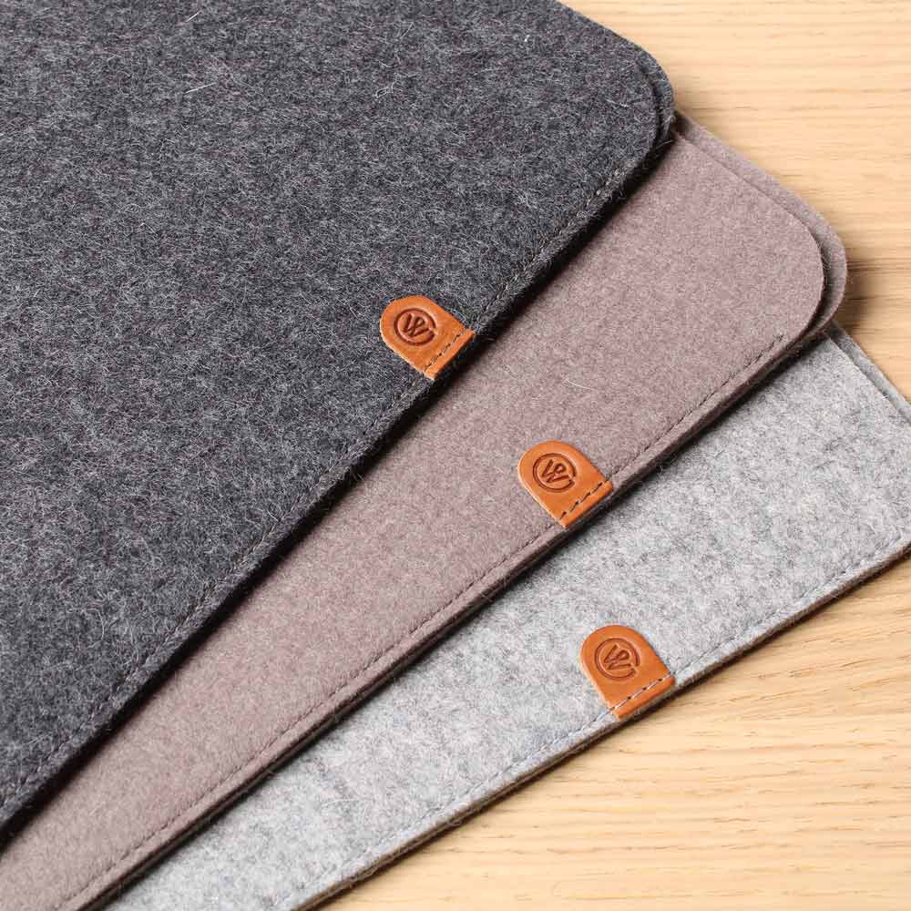 macbook neo Hüllen von Good Wilhelm aus Wollfilz in den Farben Anthrazit, Taupe und Grau liegen auf einem Tisch