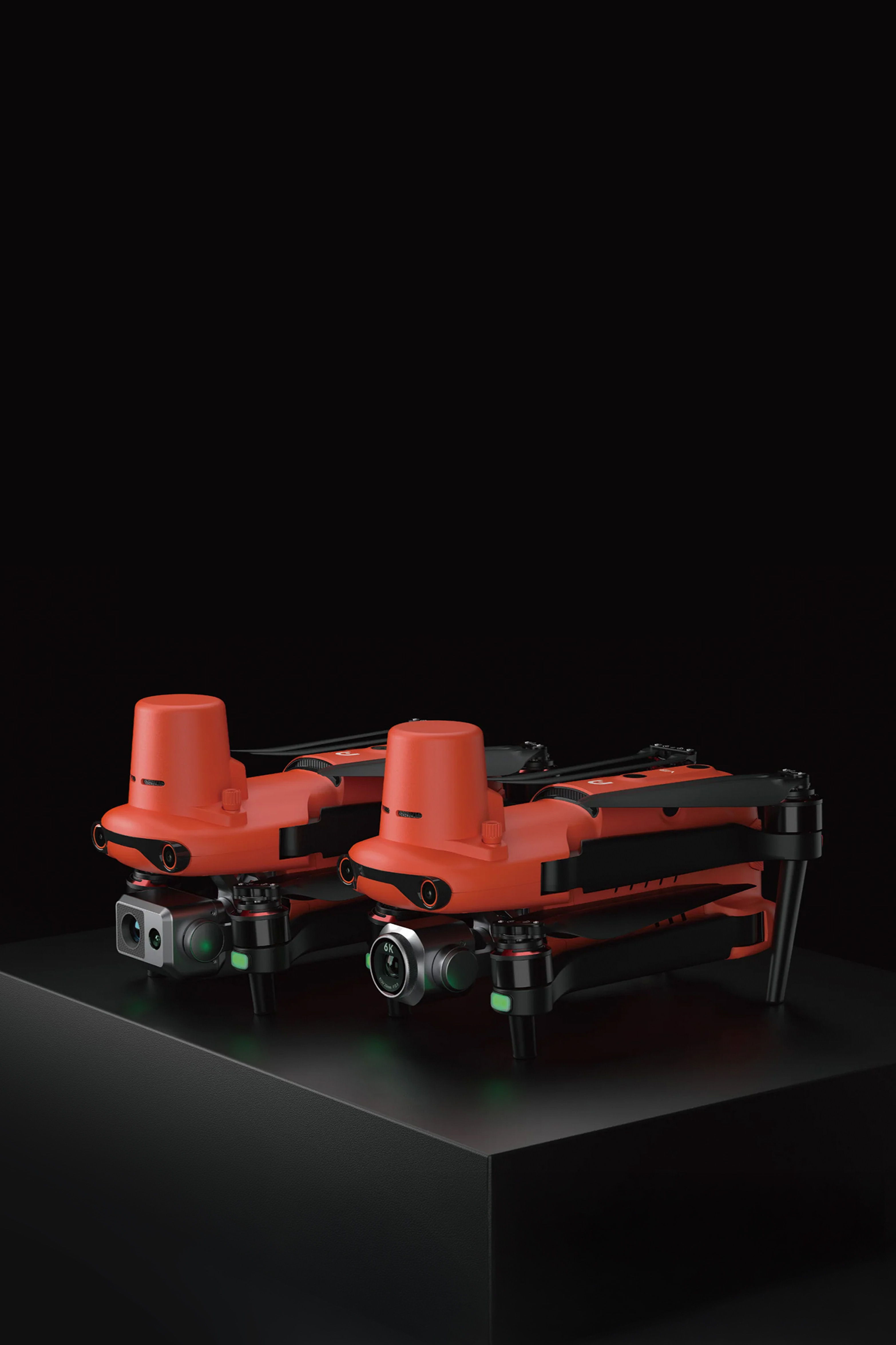 Two orange Autel EVO II drones displayed on a dark pedestal.