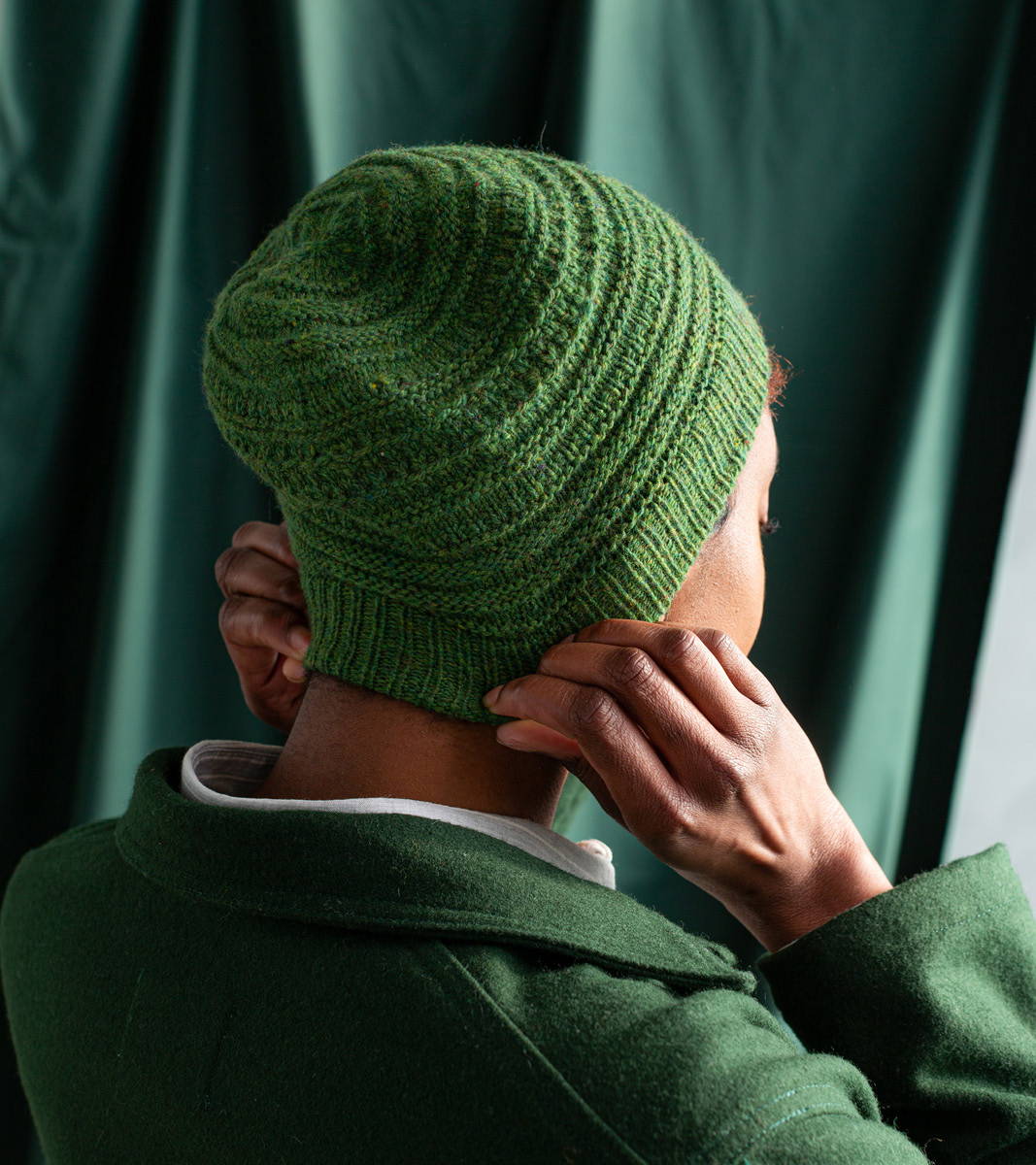 Maya, a woman with short hair. models Brooklyn Tweed hand knit Grist Hat in Imbue Sport color Hummingbird -- crown view