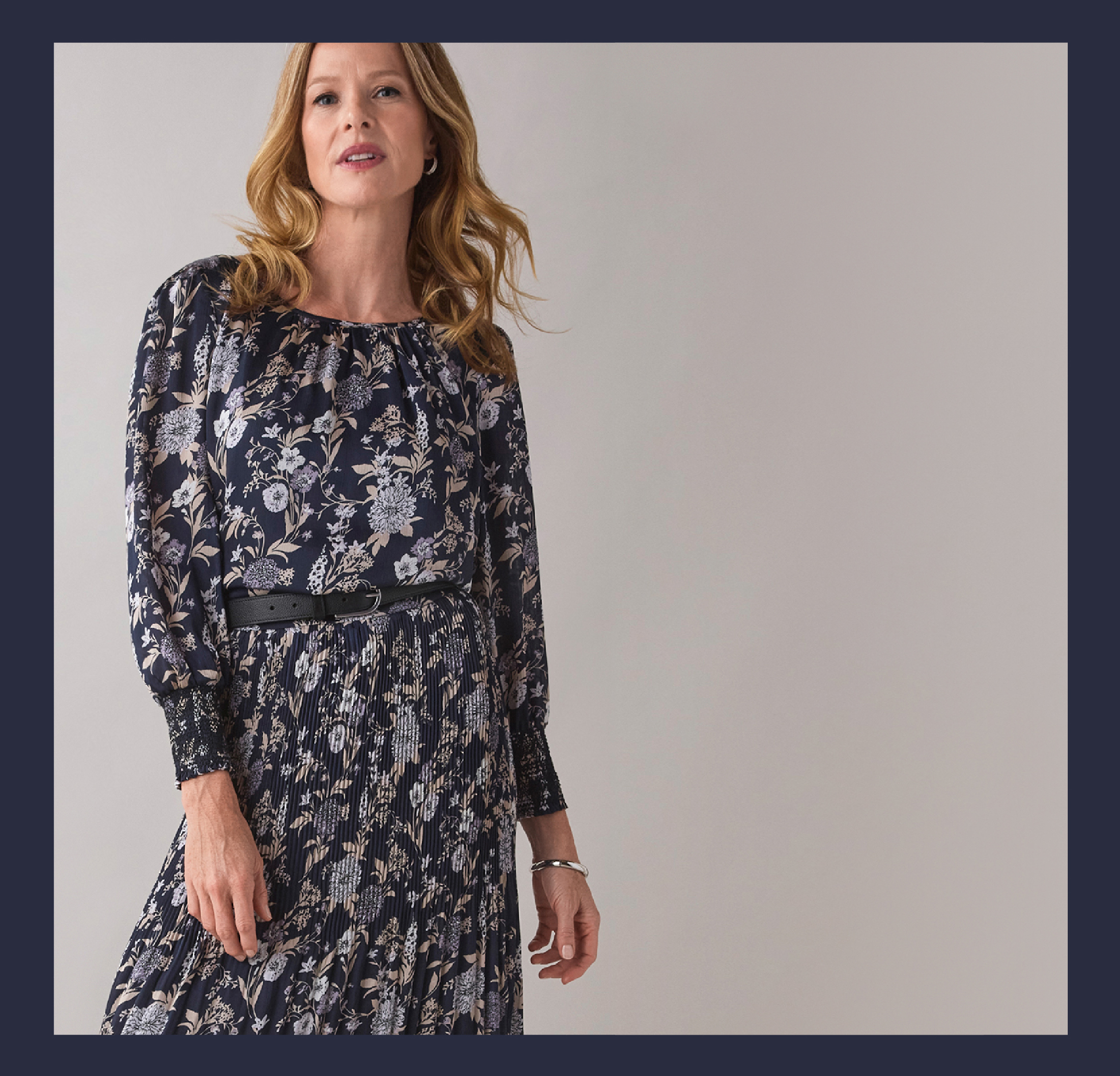 Woman in floral dress posing against a neutral background.