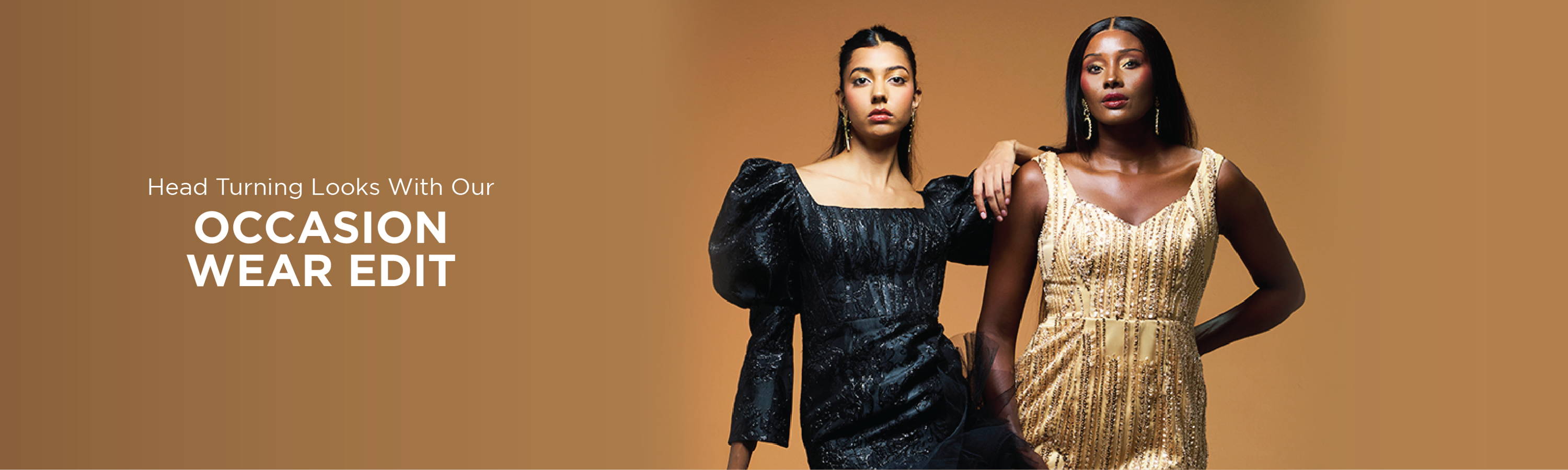 Models- Natanya Chetty in a Black Brocade and Tulle Midi-Dress by AFI Privé with Model Poppy Xaba in a beaded gold mini-dress by AFI Privé. They are standing in front of a bronze backdrop.
