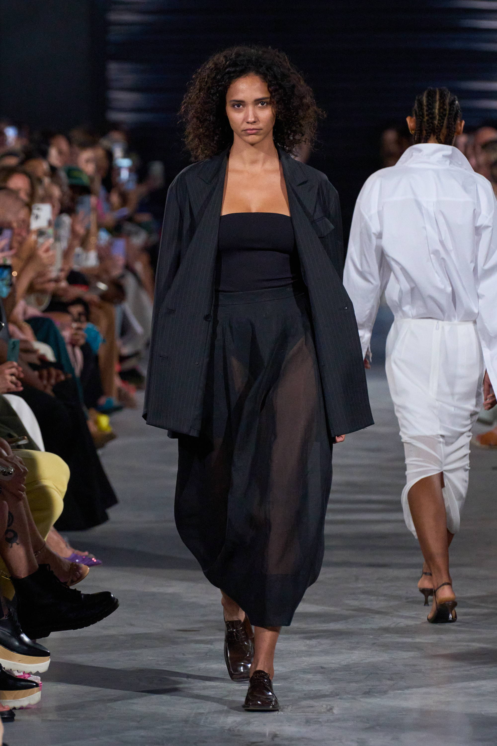 Model on a runway wearing blazer over skirt