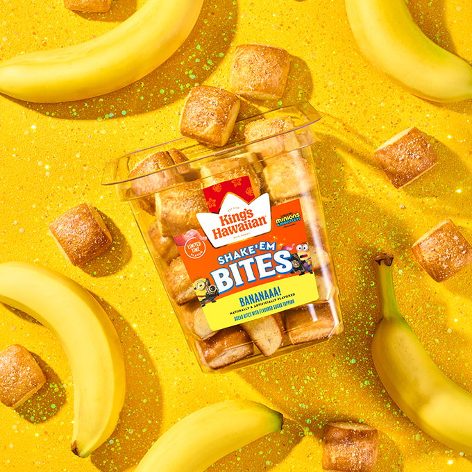 Tub of Shake 'Em Bananaaa! Bites surrounded by bananas on a bright yellow background.