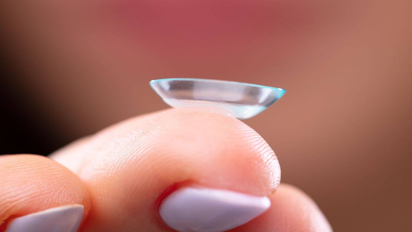 Finger holding a contact lens and inserting to eye