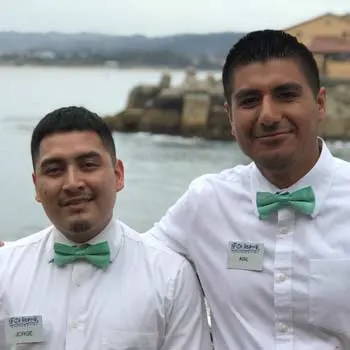 Two waiters wearing a seafoam bow tie.