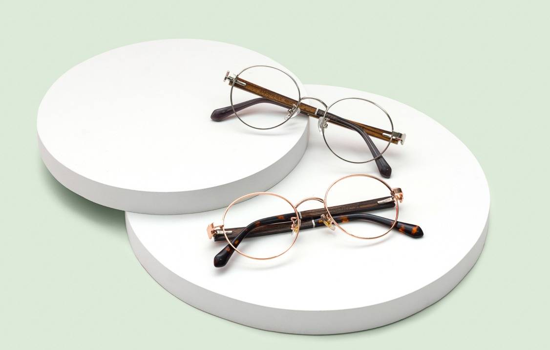 flat lay of round silver metal glasses and round rose gold metal glasses