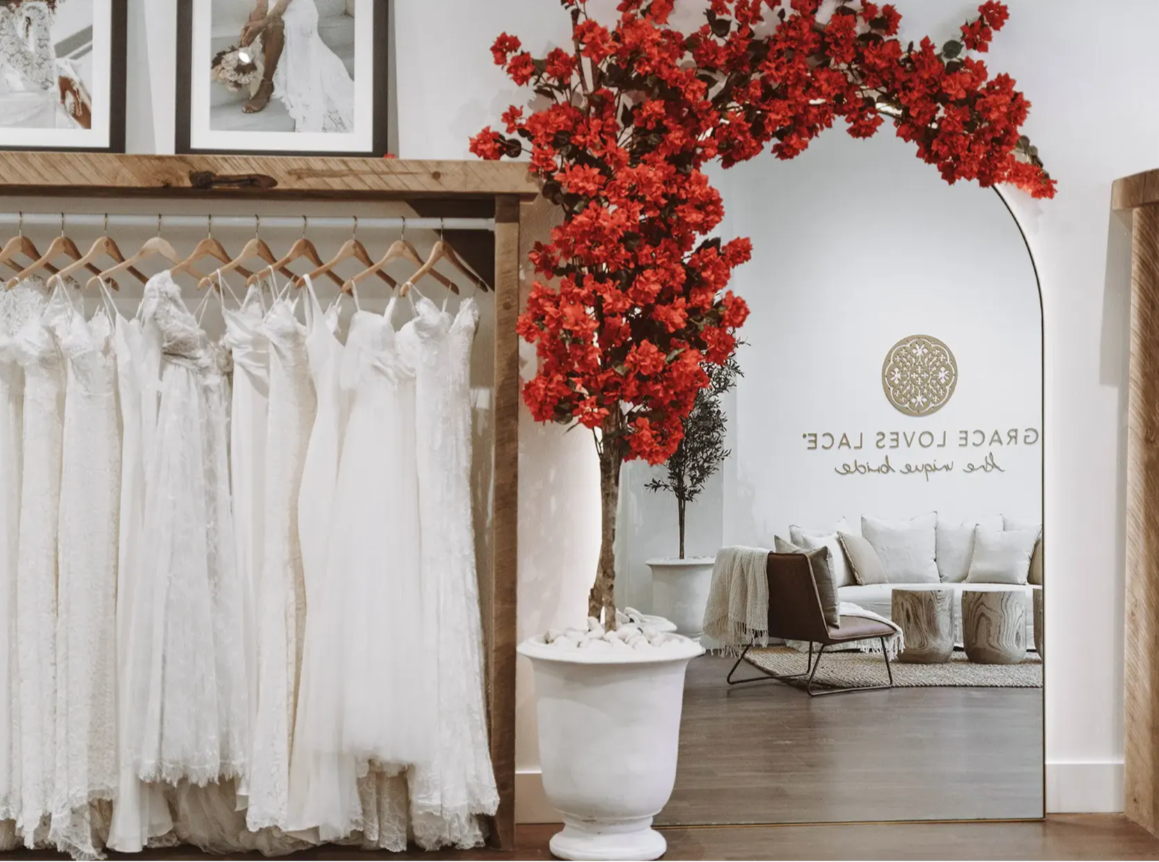 Red bougainvillea hanging over arch mirror in white pot in Grace Loves Lace bridal showroom