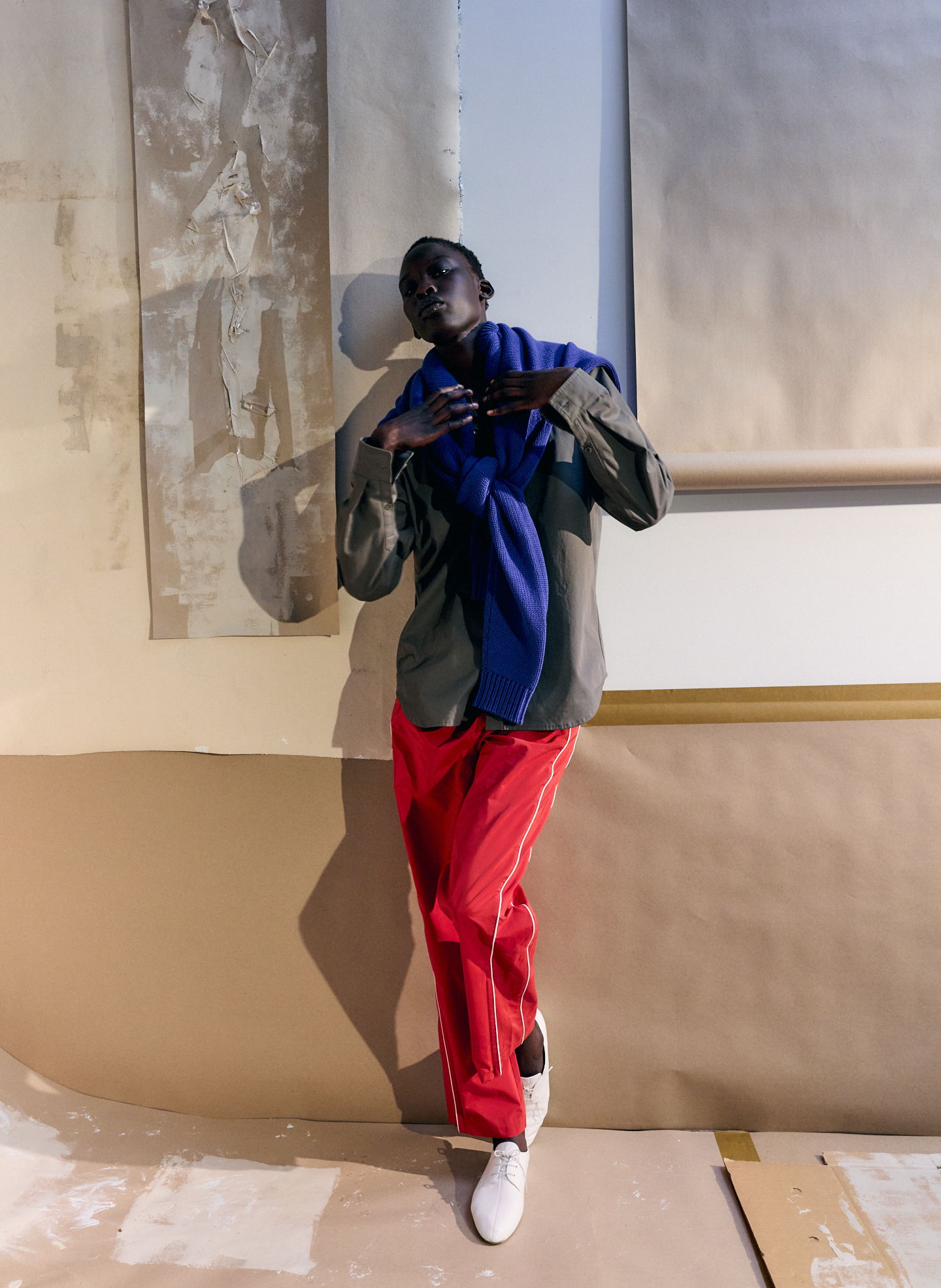 Person posing in colorful clothing against a minimalist background.