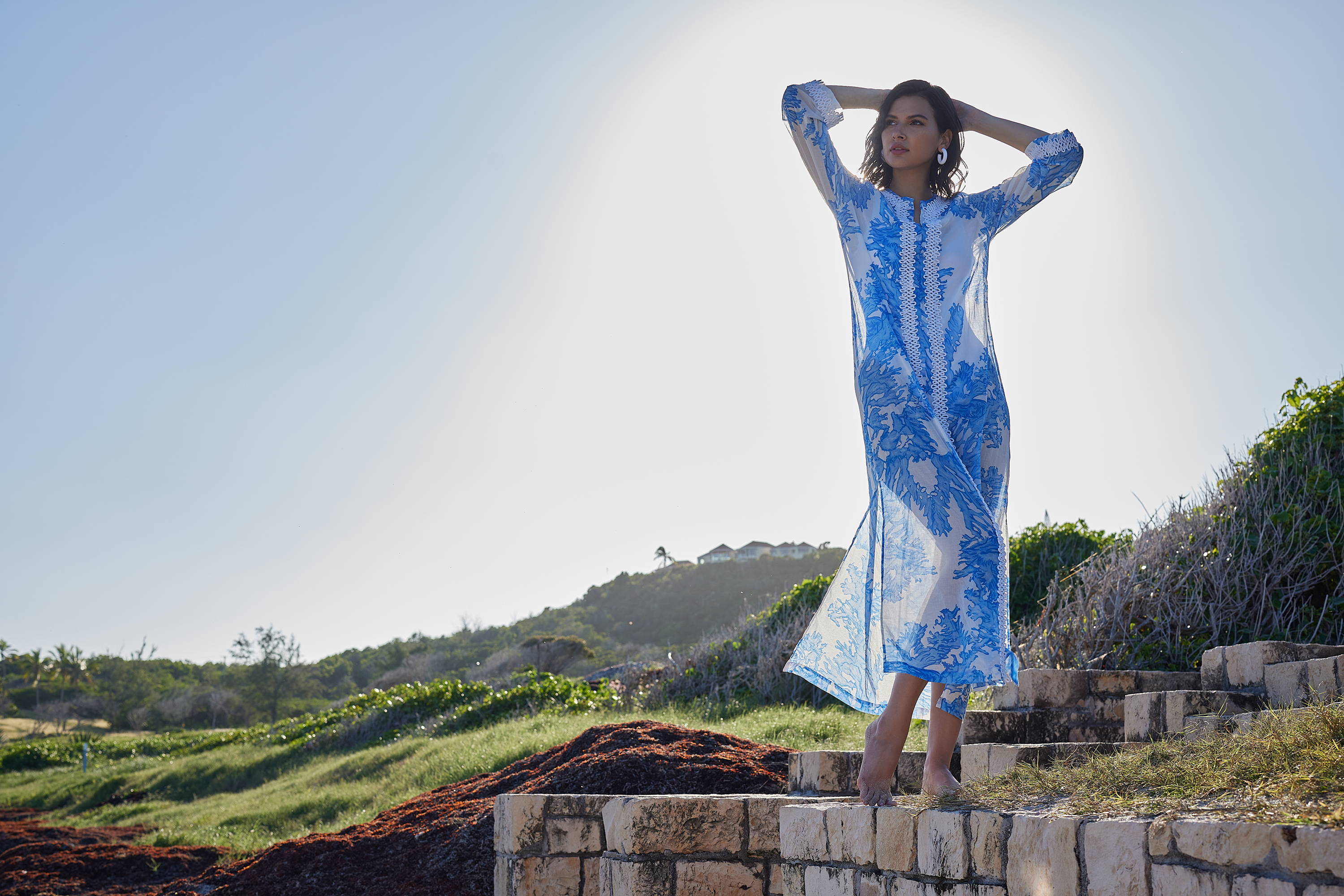 Woman wearing blue coral printed cotton kaftan with white trim by Ala von Auersperg for resort 2023