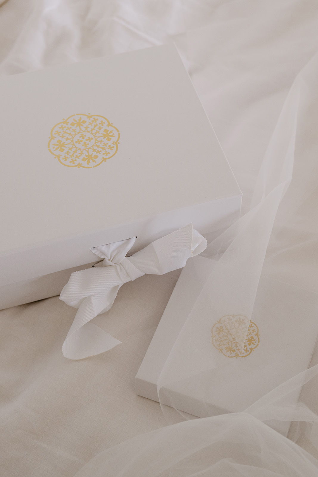 White gift boxes with gold accents on a soft fabric background.