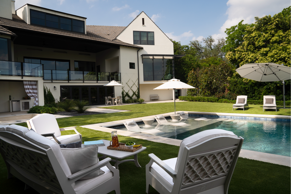 Poolside backyard layout with outdoor lounge chairs, in-pool seating, umbrellas, and separate patio zones for relaxing and entertaining.