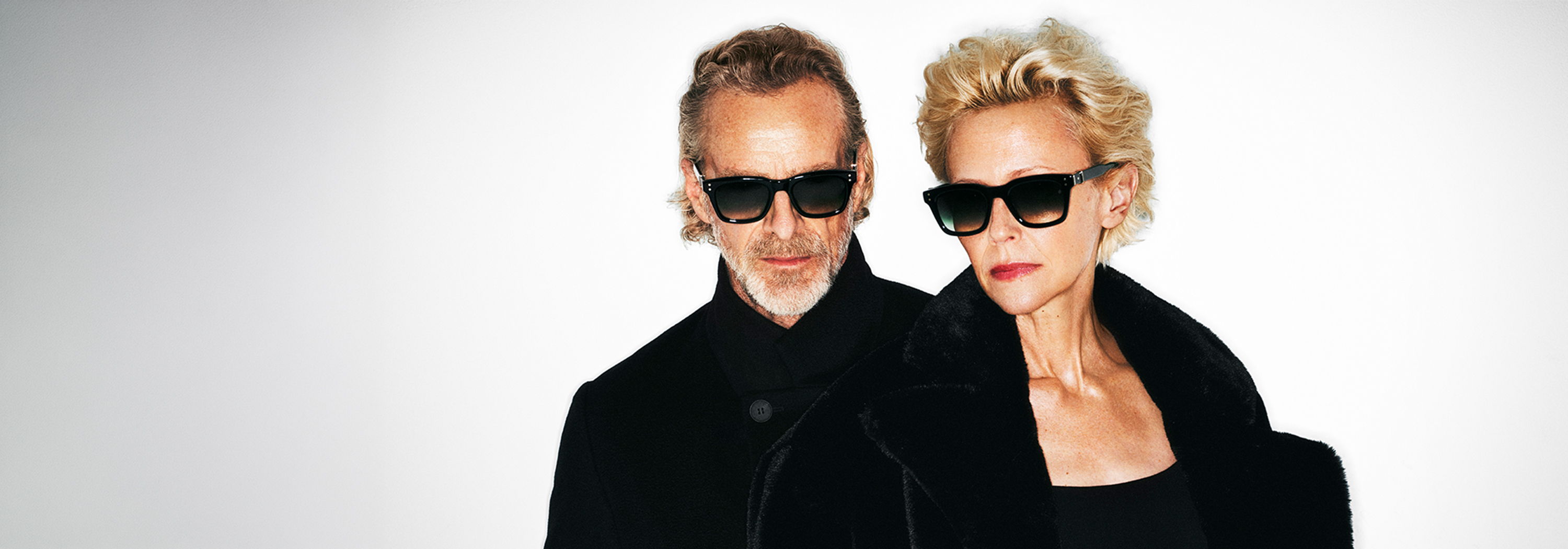 Two stylish individuals wearing Robert Marc sunglasses against a minimalist background.