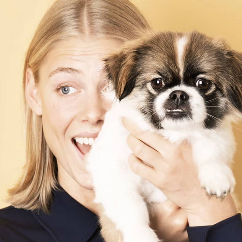 Giovane donna che tiene in braccio un cagnolino e forse ha una congiuntivite allergica.