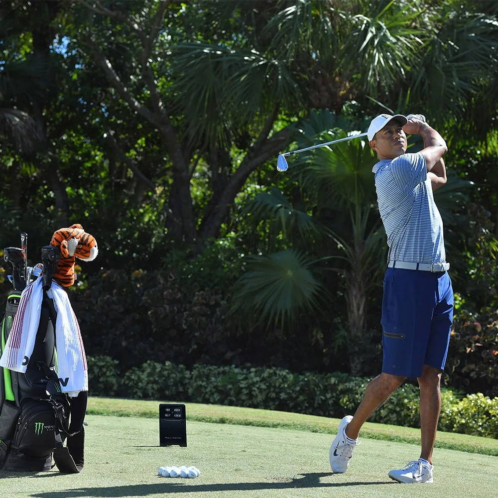 Tiger Woods hitting out on the golf range with his golf clubs and the Full Swing KIT