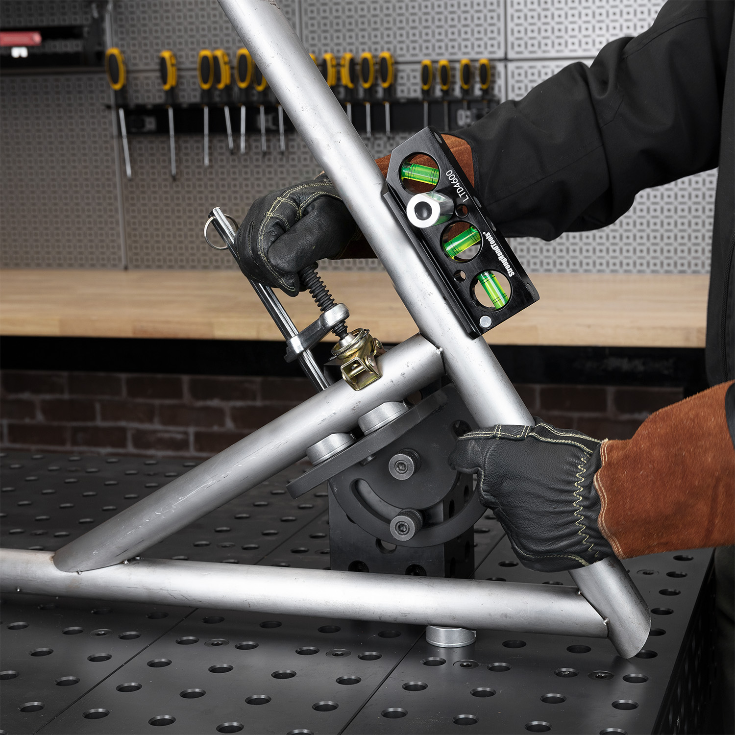 Person using a level tool on metal tubing at a workbench.