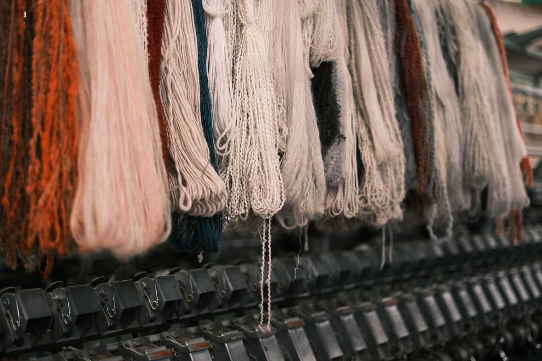Colorful strands of yarn hanging on a display rack.