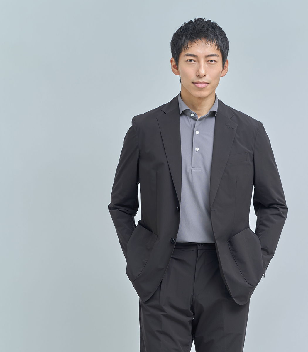 A young man in a suit against a light gray background.