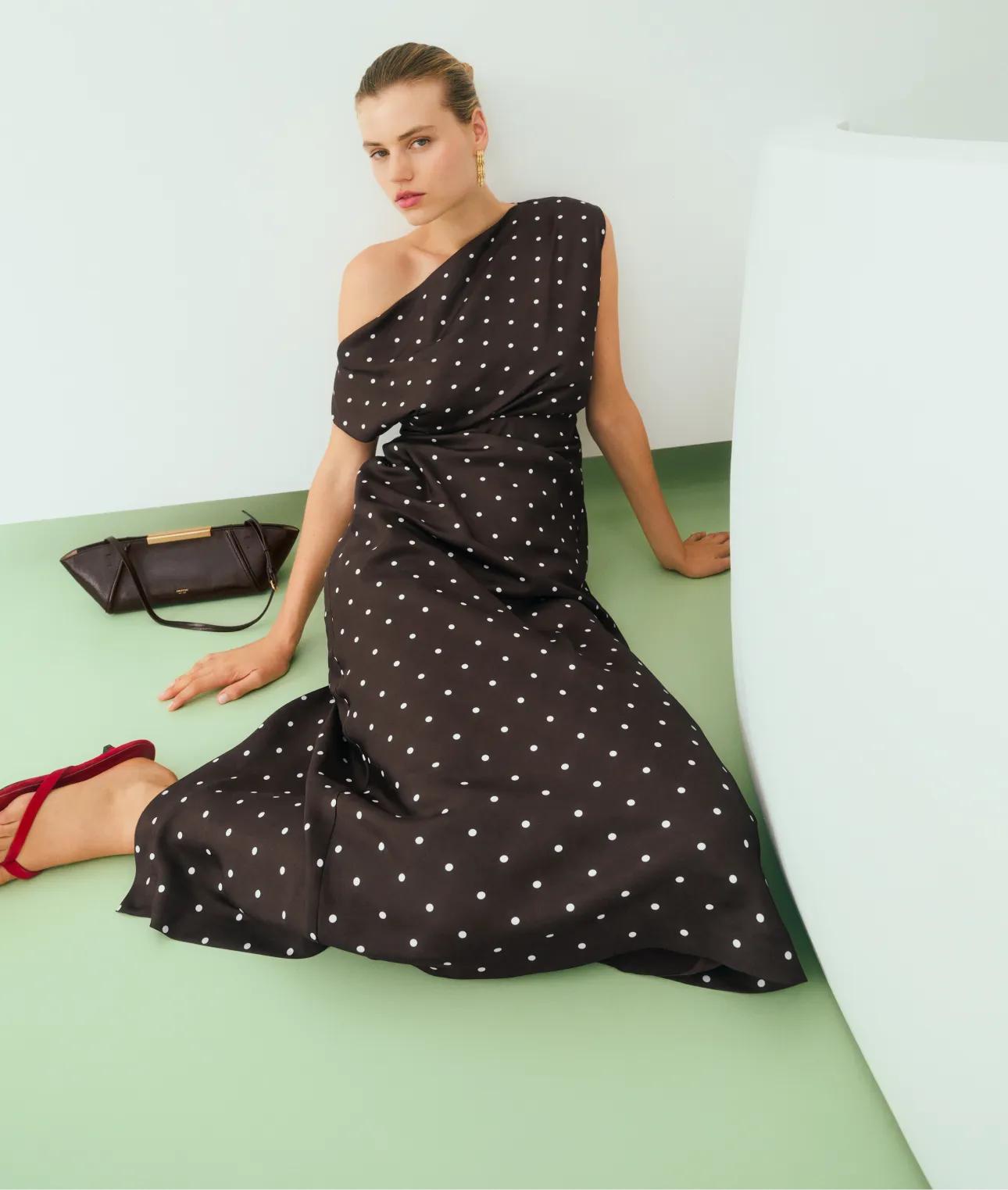 Woman in a polka dot dress sitting on a light green floor.