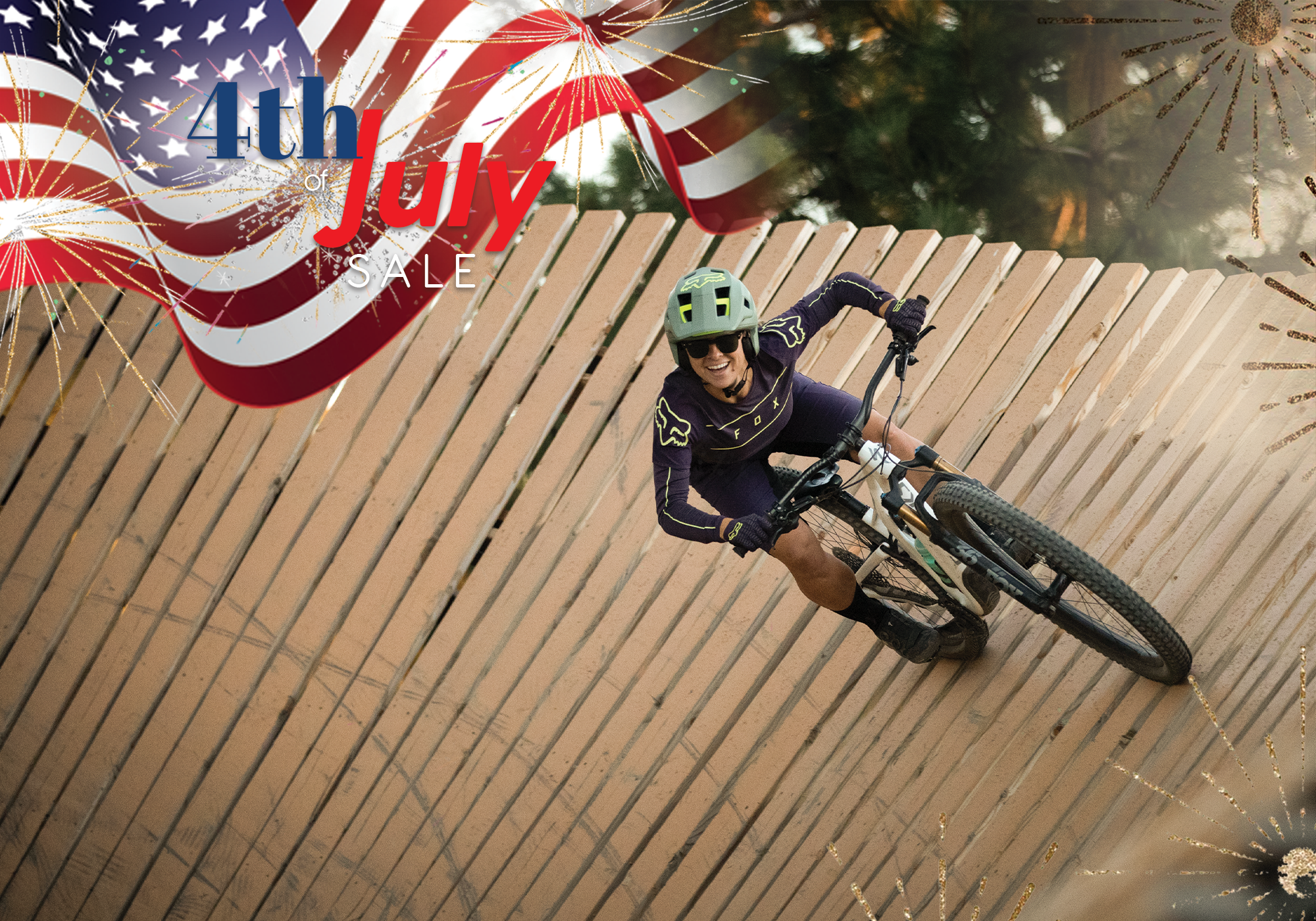 4th of july sale flag and firework logo over an image of a woman mountain biking