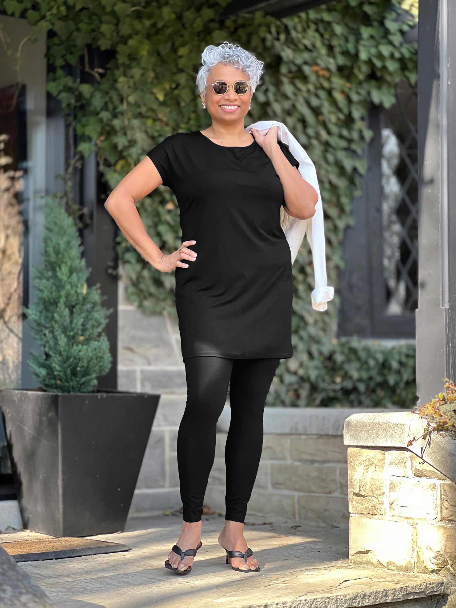 Woman standing wearing Miik's Sia dolman-sleeve cocoon tunic in black with leggings