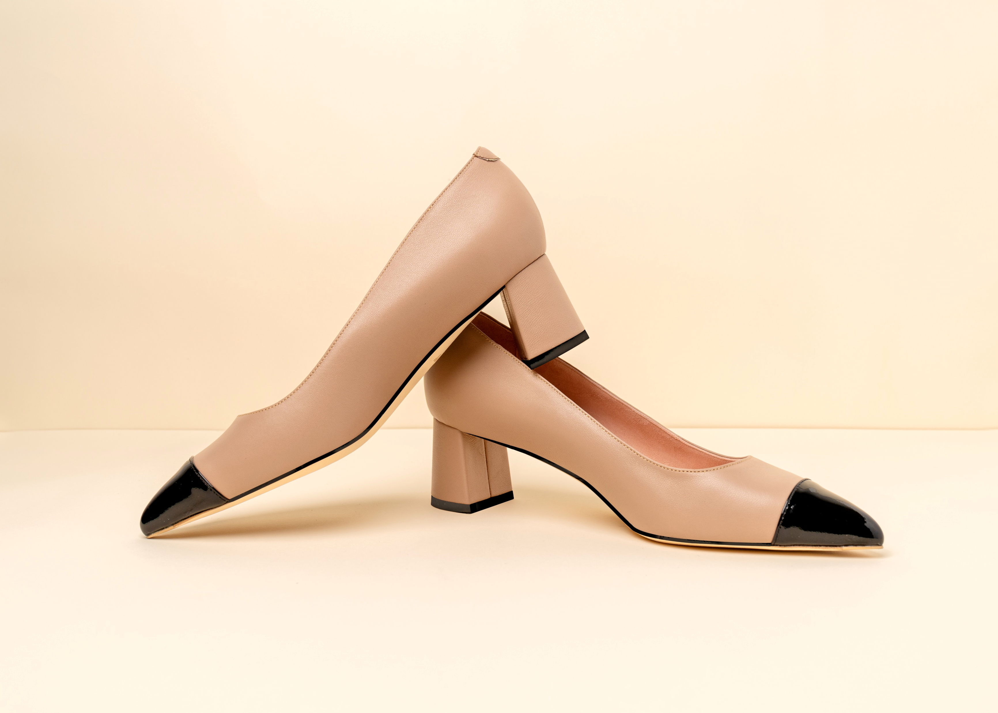Beige high heel shoe with a black toe cap.
