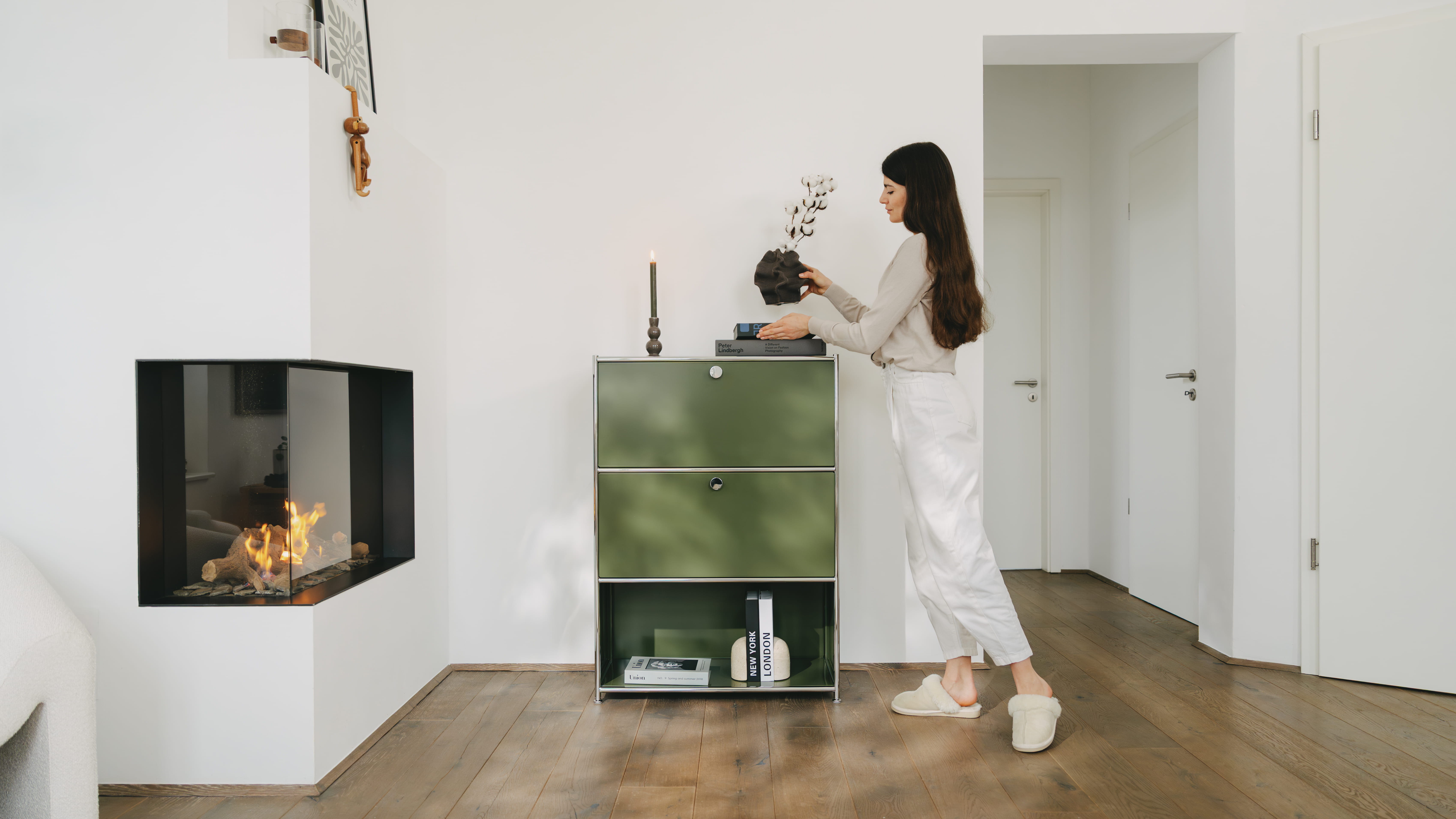 A woman sets up the olive-green " Cubox " office shelf from ofinto in her apartment