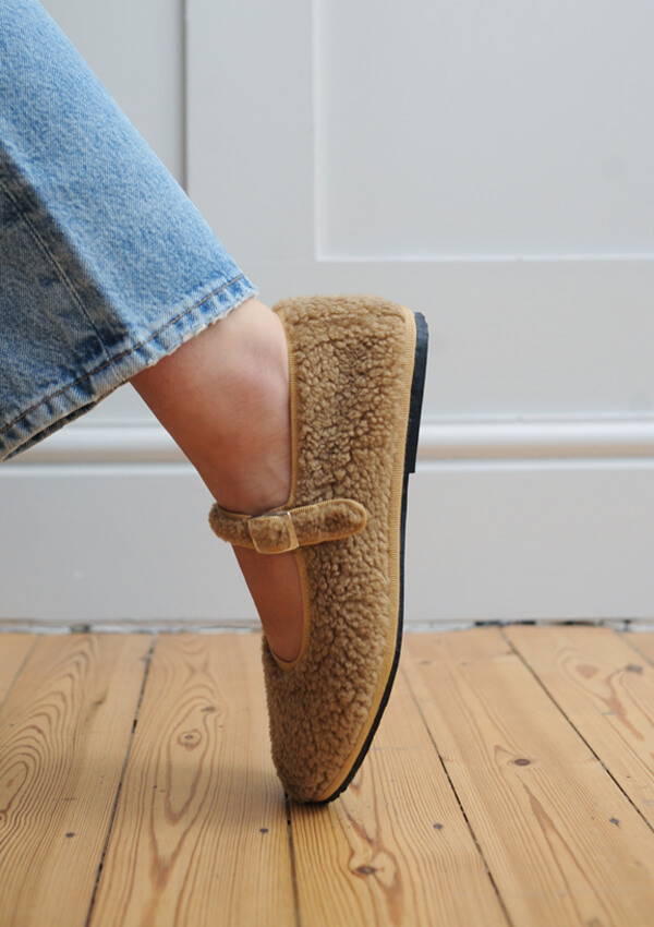 A styled image of a model foot on point wearing the Drogheria Crivellini Fleece Mary Janes in camel.