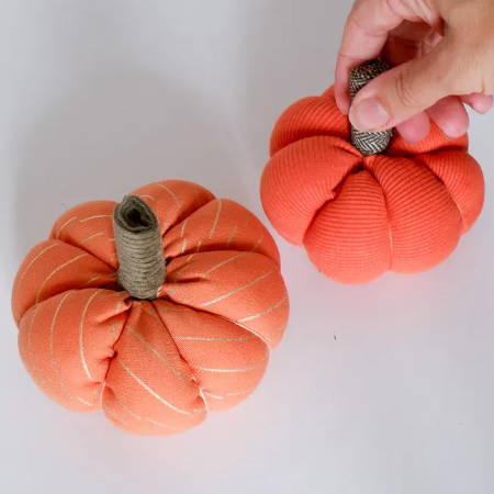 Two finished fabric pumpkins made out of orange fabrics