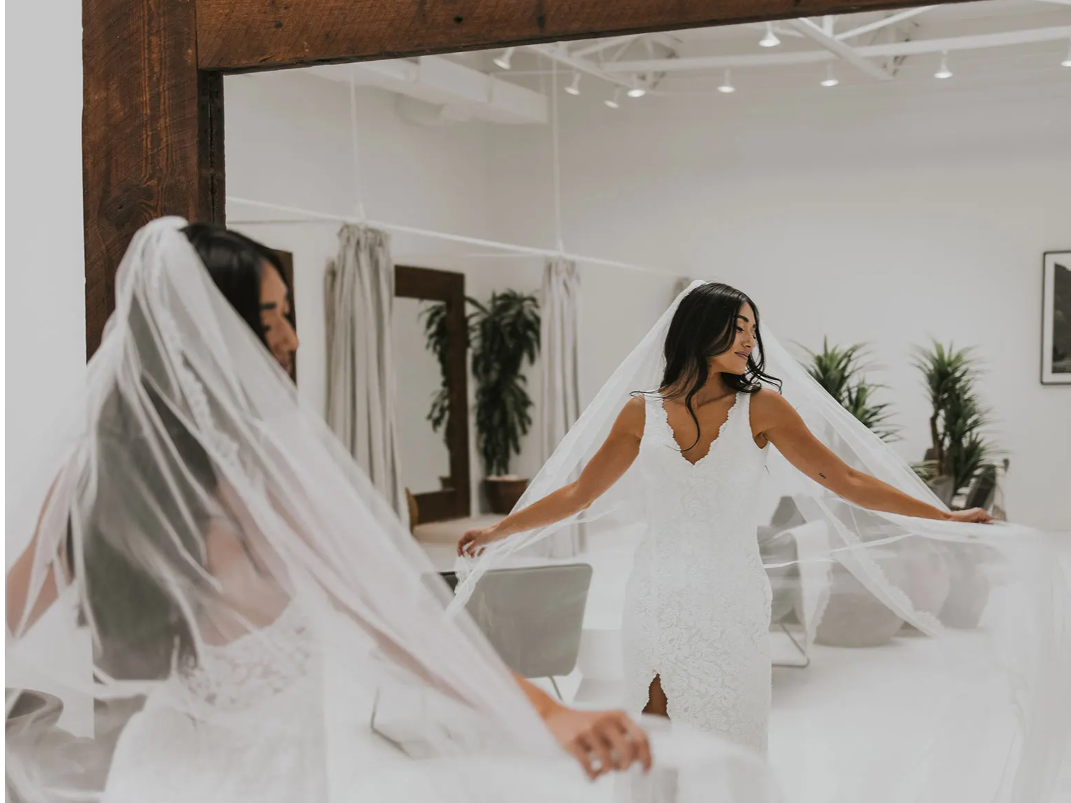 La mariée dans le miroir portant la robe de mariée Lumi et le voile Lumi. 