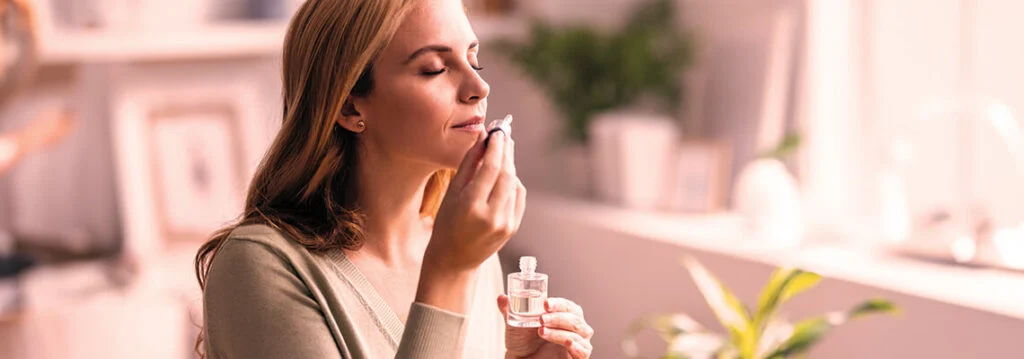 Woman applying skincare product in a bright, indoor setting.