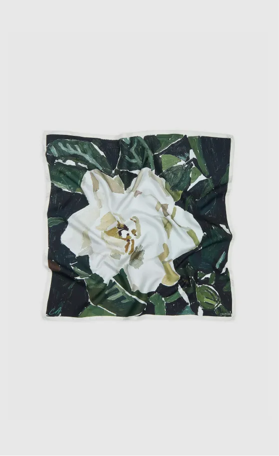 A folded scarf featuring a white flower and green leaves design.
