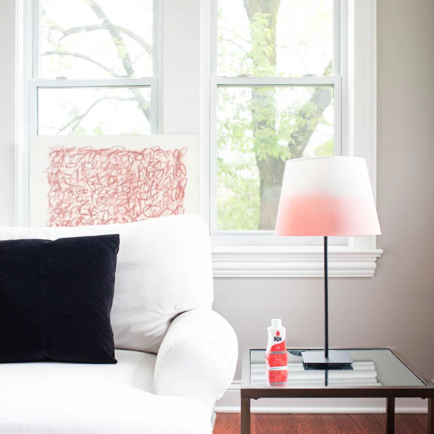 Cozy living room with a lamp, pillow, and a bottle on a table.