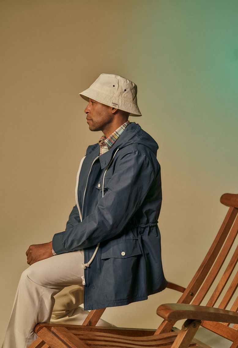 Person sitting on a chair, wearing a blue jacket and white bucket hat.