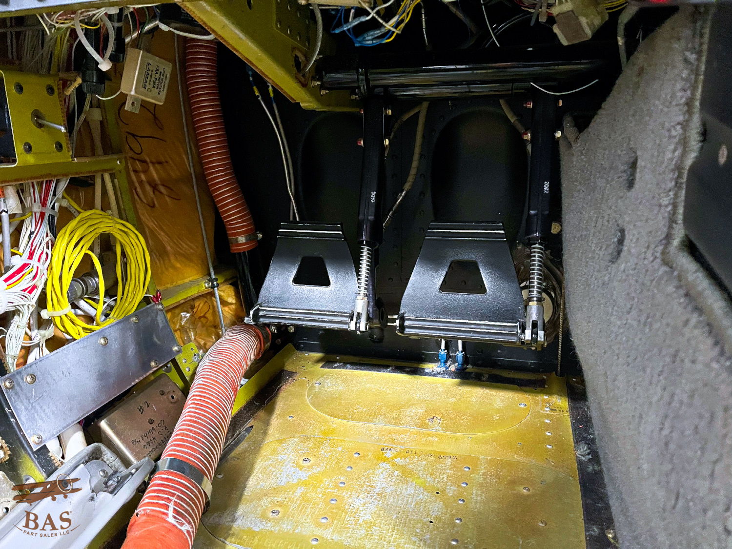 Interior view of machinery with two black seats and various cables.