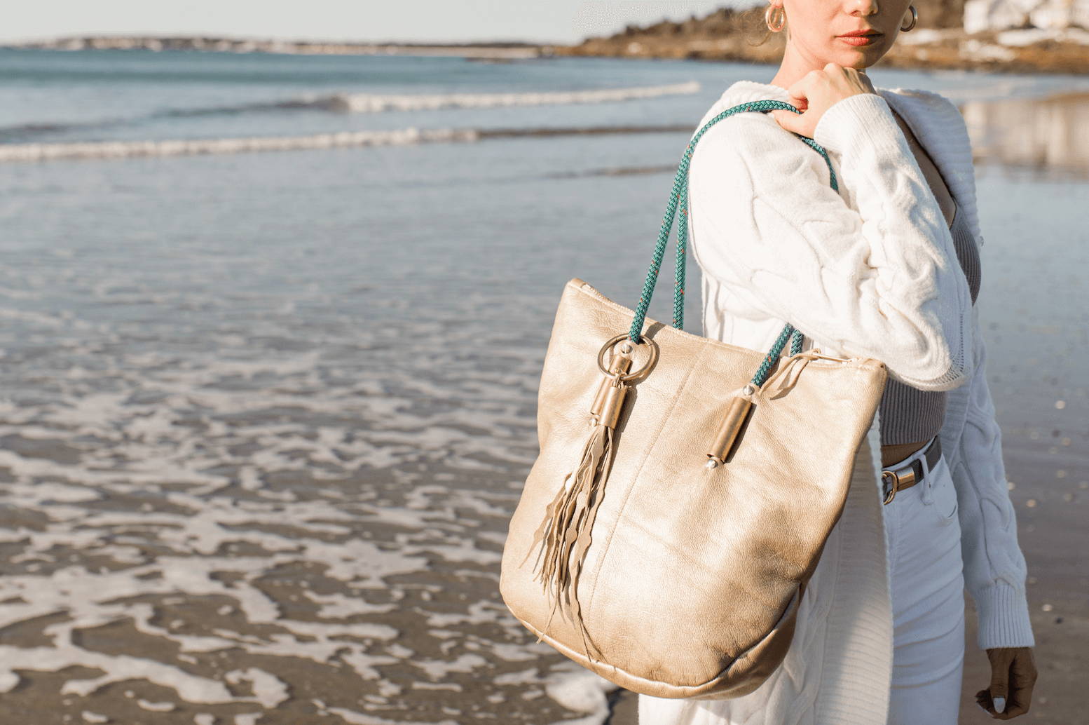 woman wearing a gold metallic leather tote on the beach