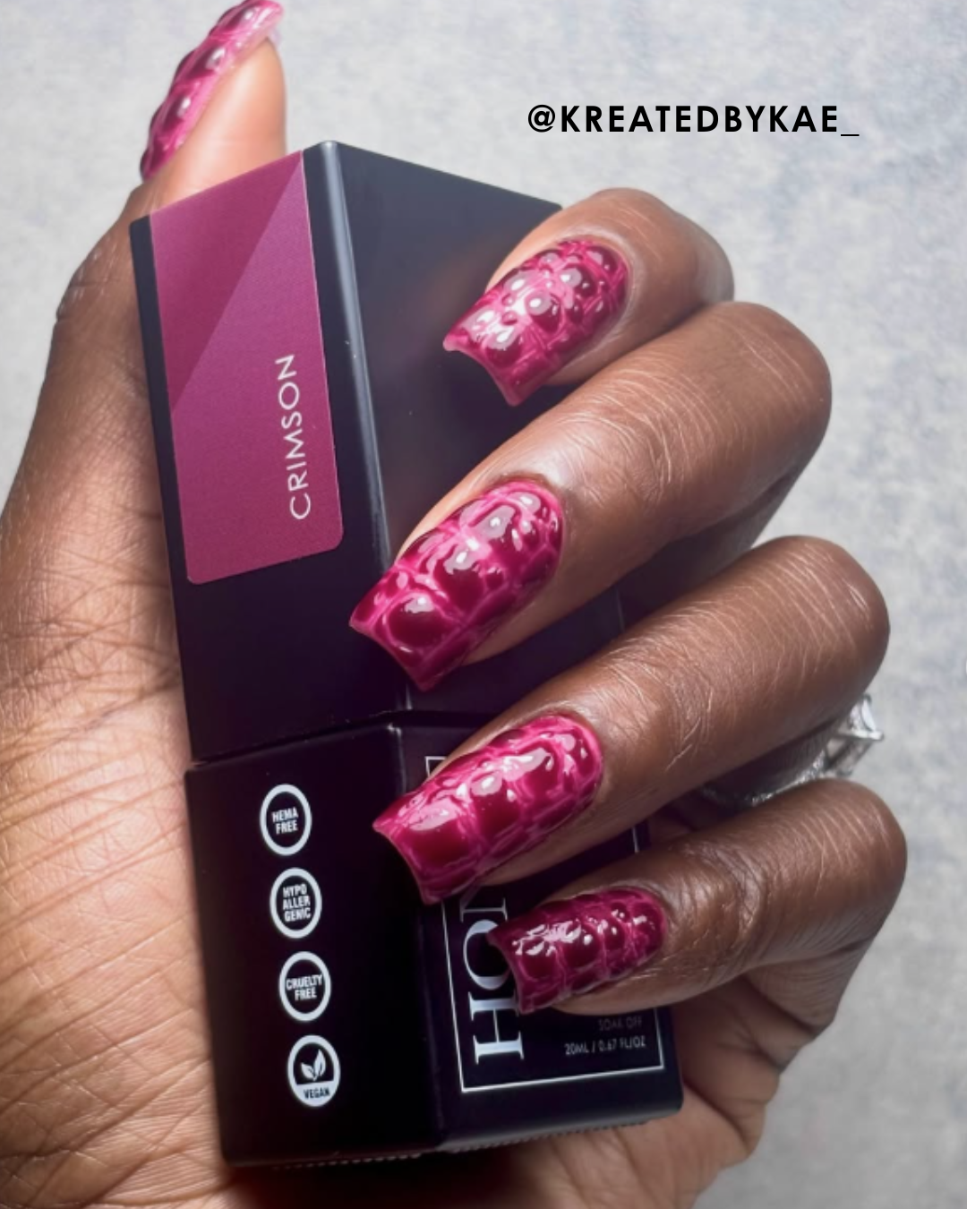 A hand displaying manicured nails holding a nail polish bottle.