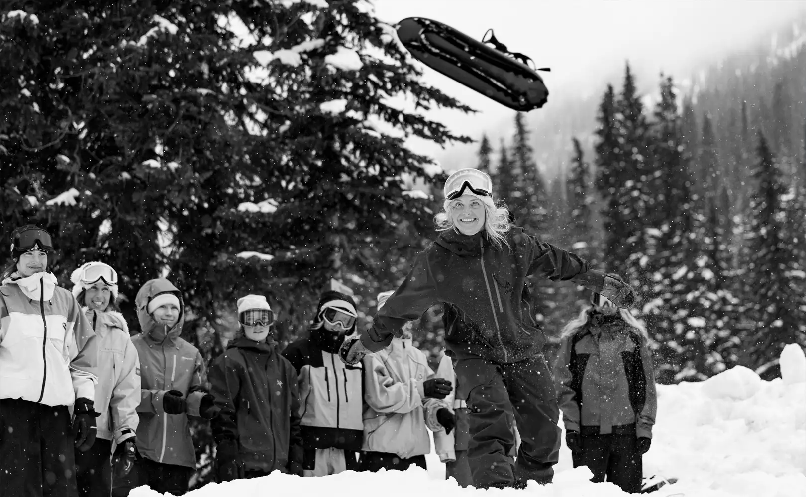 Person throwing a sled with a crowd watching in a snowy landscape.