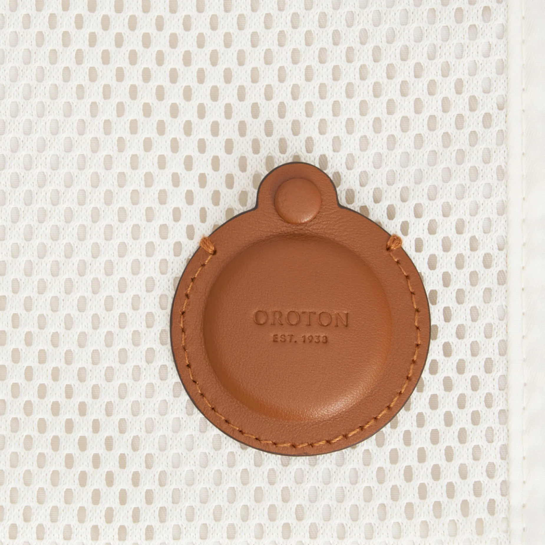 Brown circular leather tag on a textured white background.
