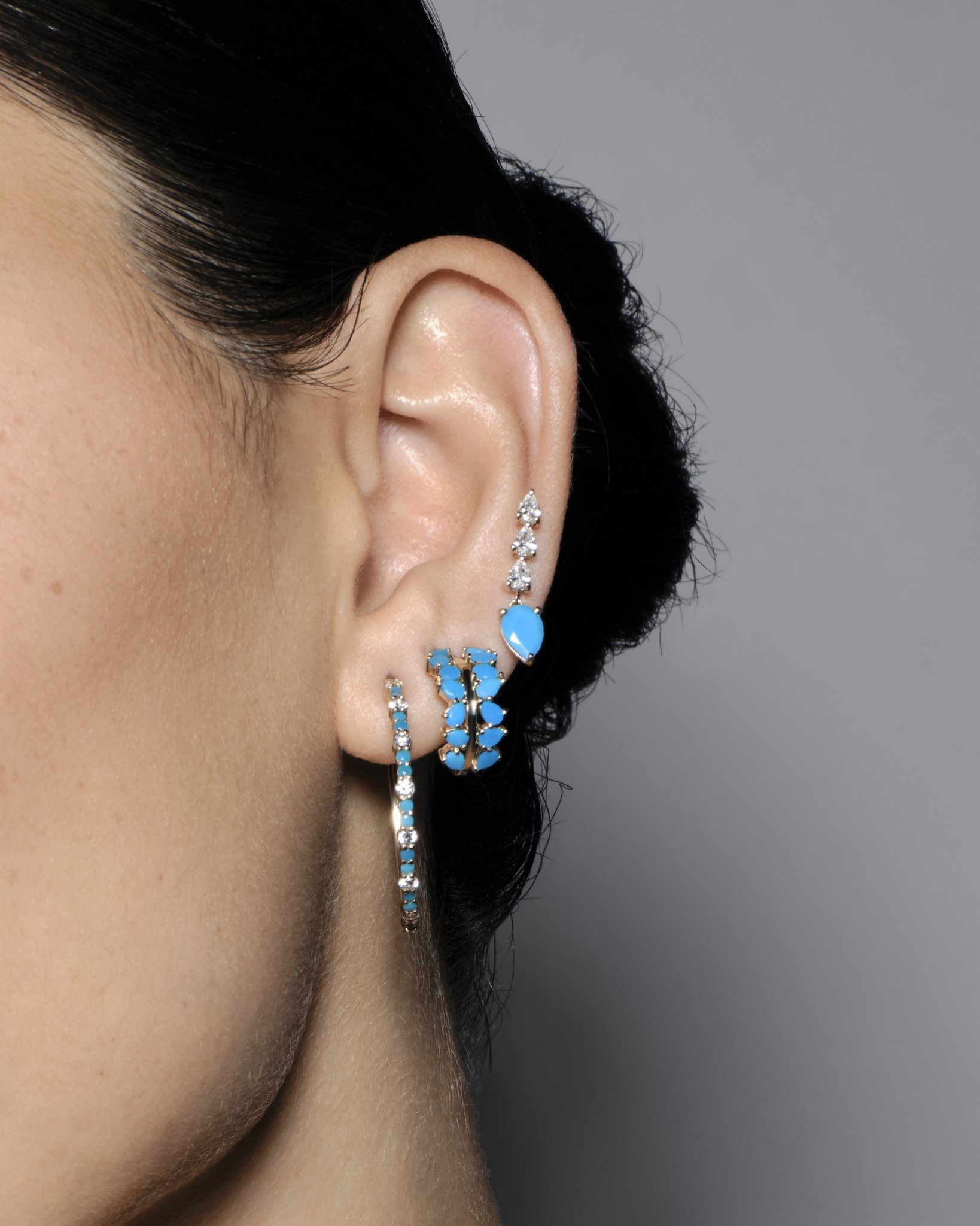 Close-up of an ear adorned with various stylish earrings.