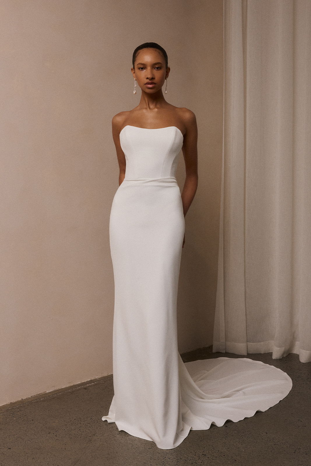 Model wearing a sleek white strapless gown against a neutral background.