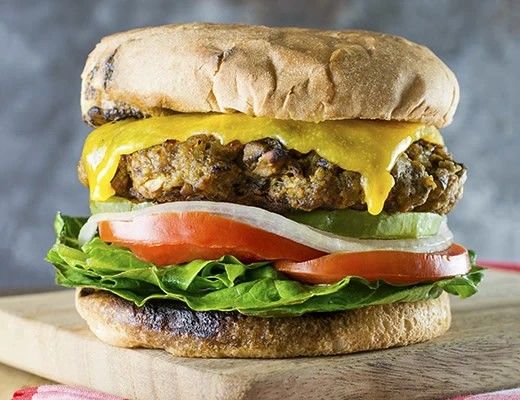 A close-up of a cheeseburger with lettuce, tomato, and pickles.