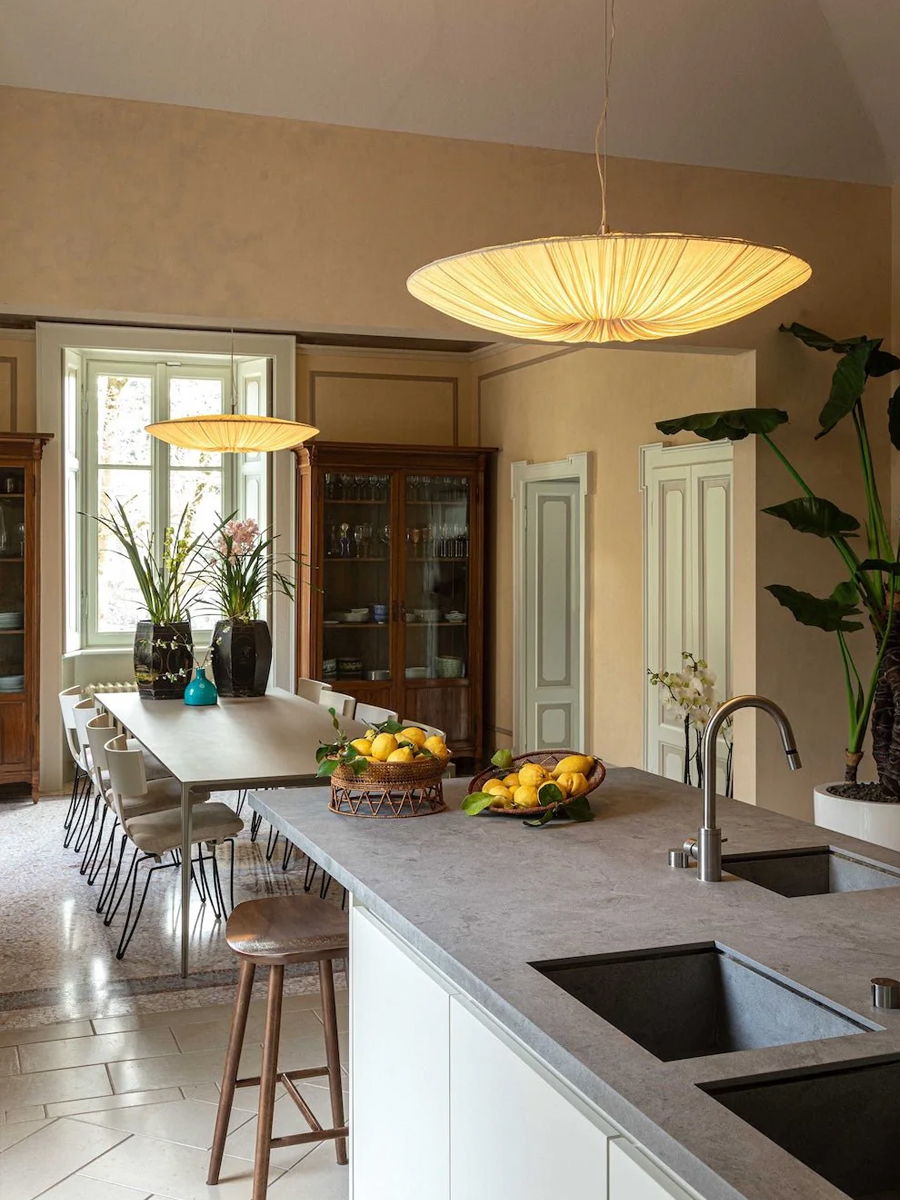Modern kitchen with a large island, stylish lighting, and decorative plants.