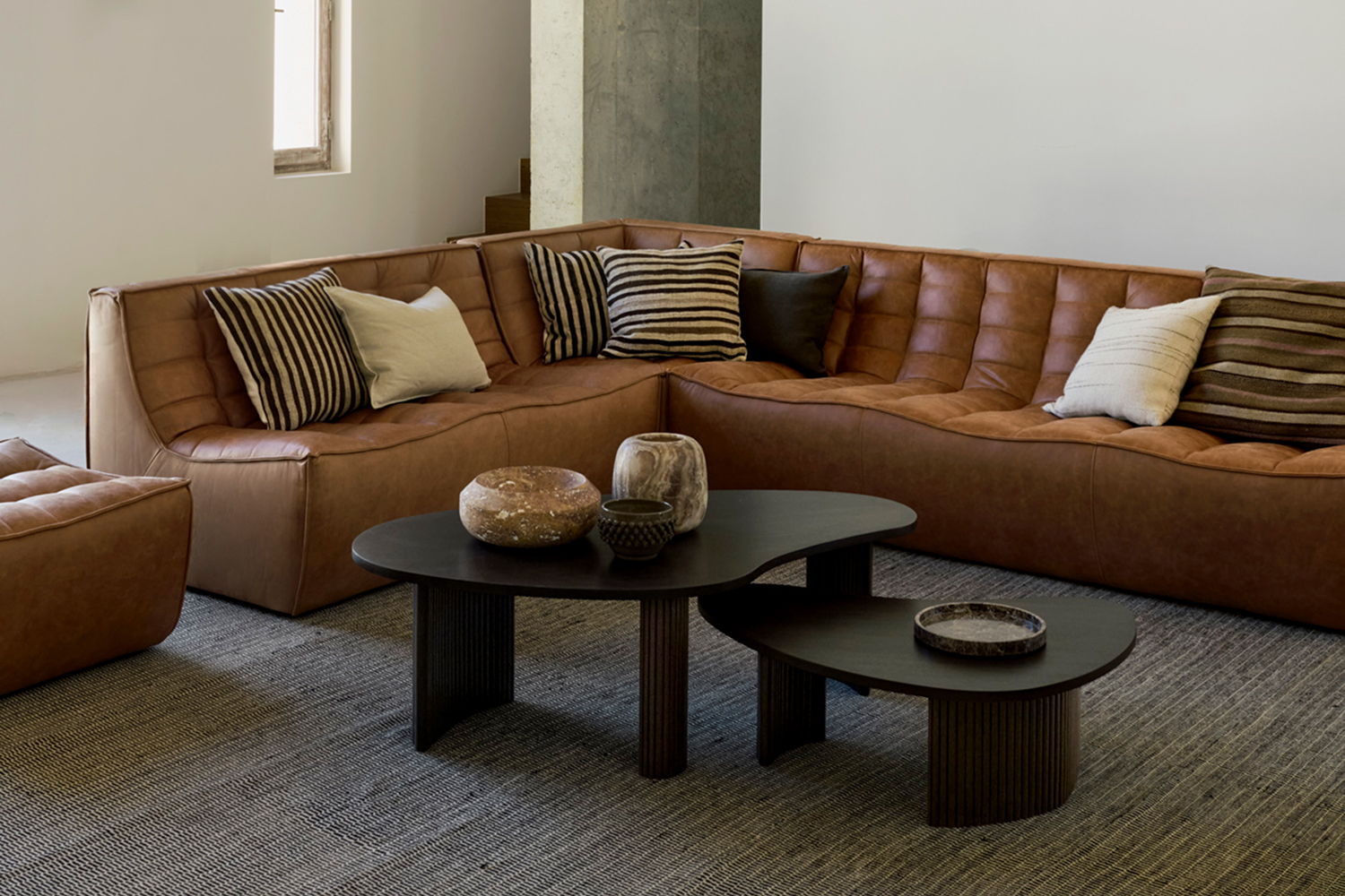Modern living room with a brown sectional sofa and black coffee tables.