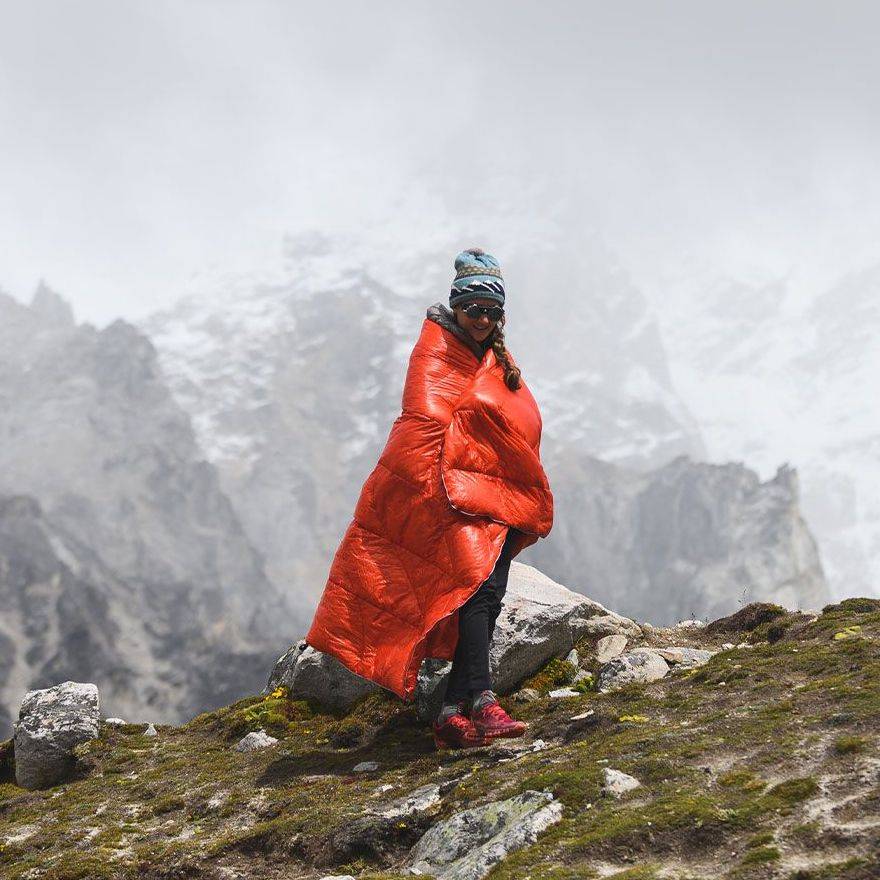 Woman at base camp of Mt. Everest wrapped in Mountain Hardwear Rumpl down blanket
