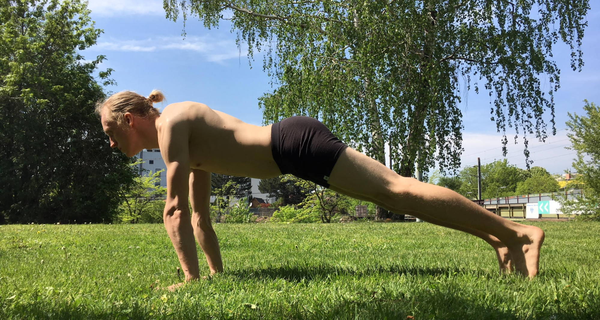 A man wearing some of the best workout underwear (WAMA hemp underwear) while doing yoga in a park.