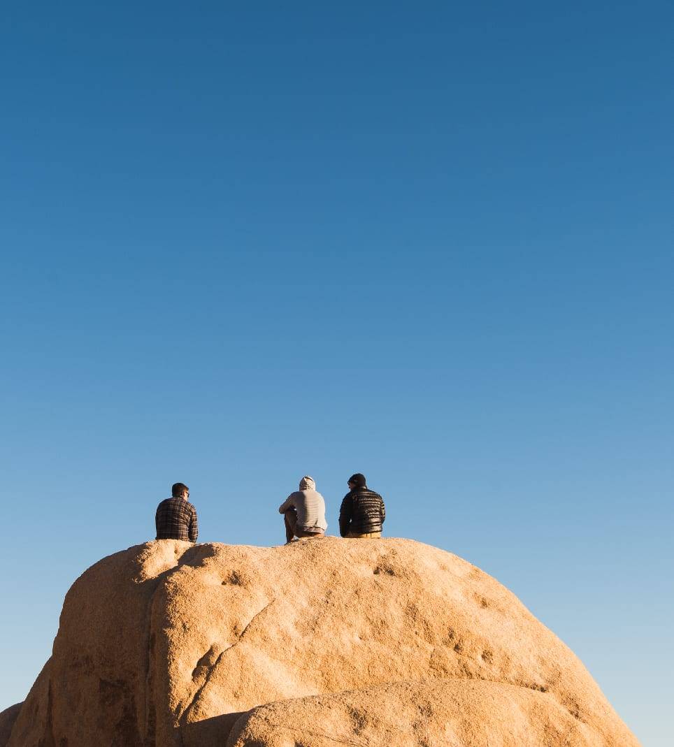Three men taking in the view on a high boulder