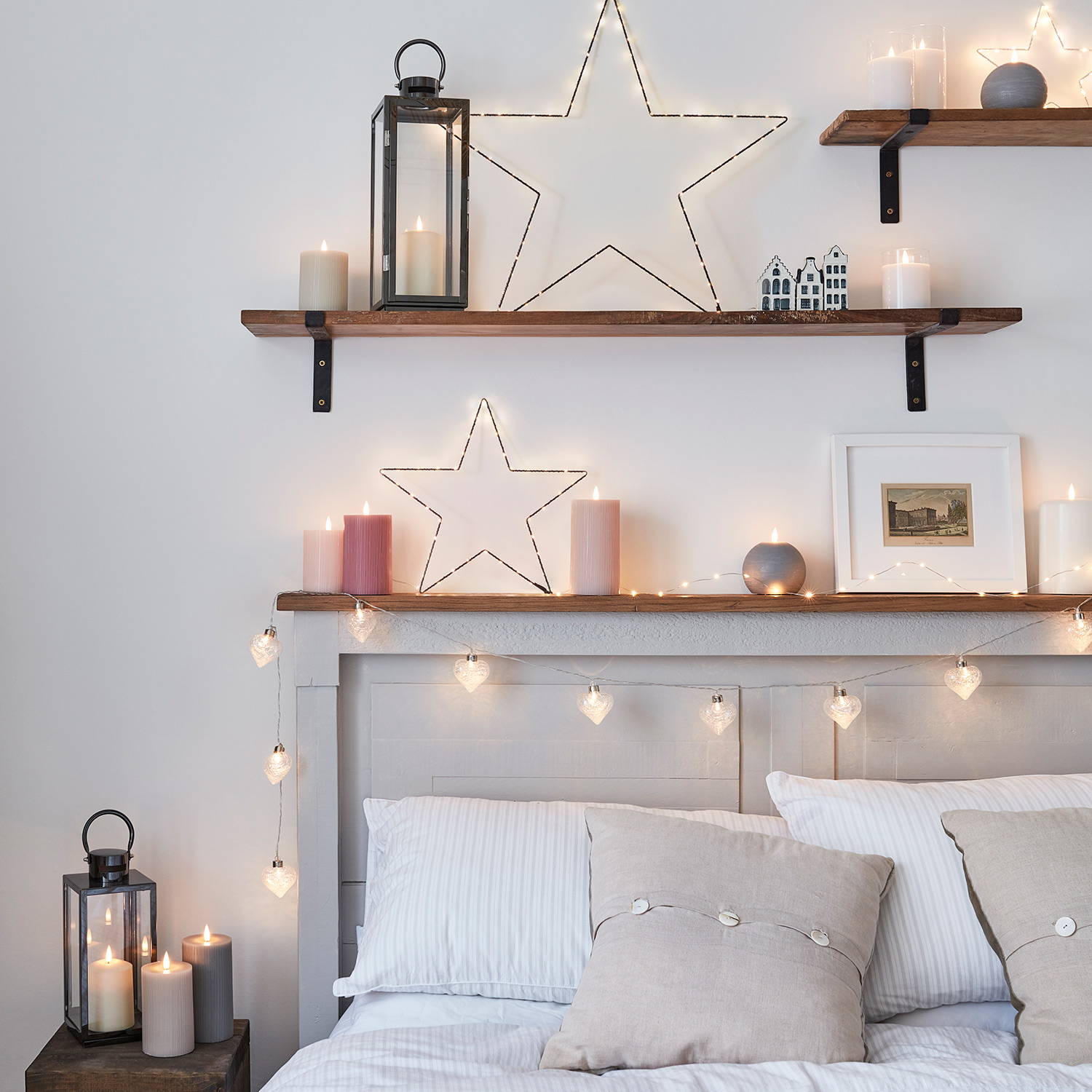 A bedroom setting with LED candles, lanterns, fairy lights and osby stars hanging on shelves.
