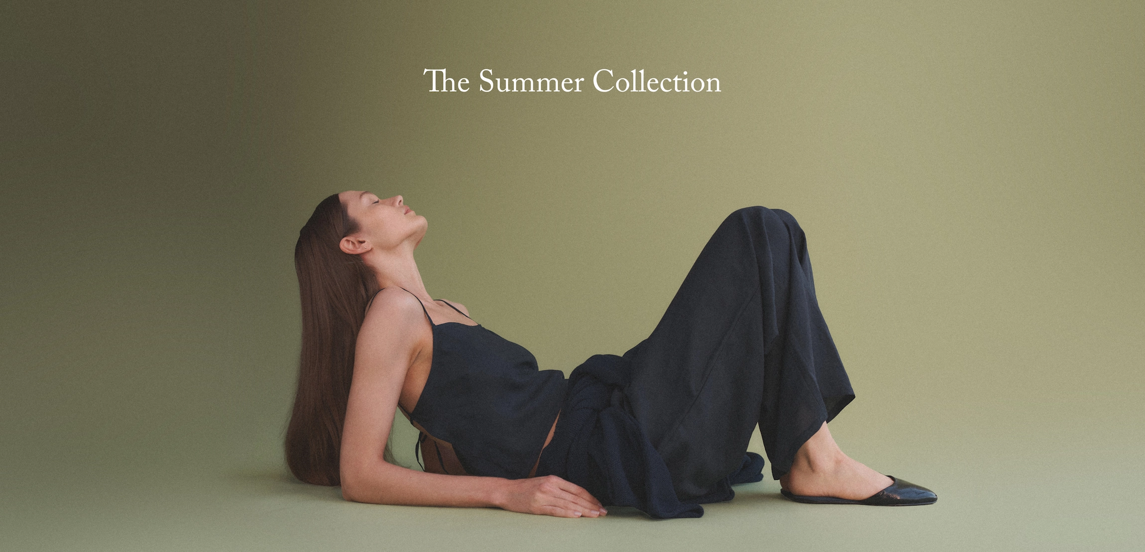 text: The Summer Collection. Woman laying on back propped up on elbows