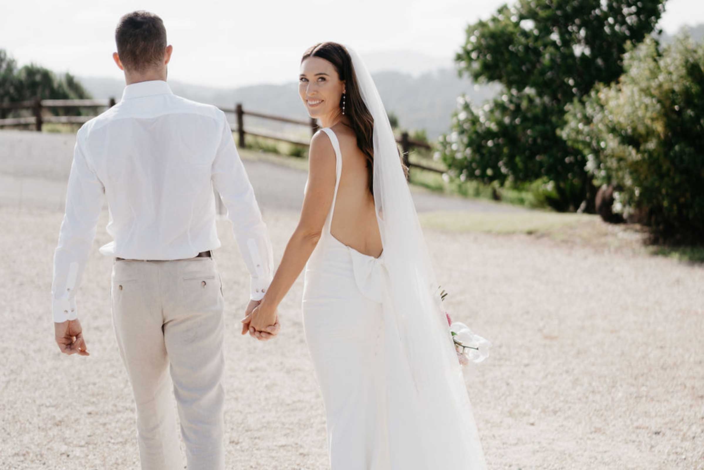 Intimate shot of the bride and groom holding each other from behind, with the bride's back facing the camera. 